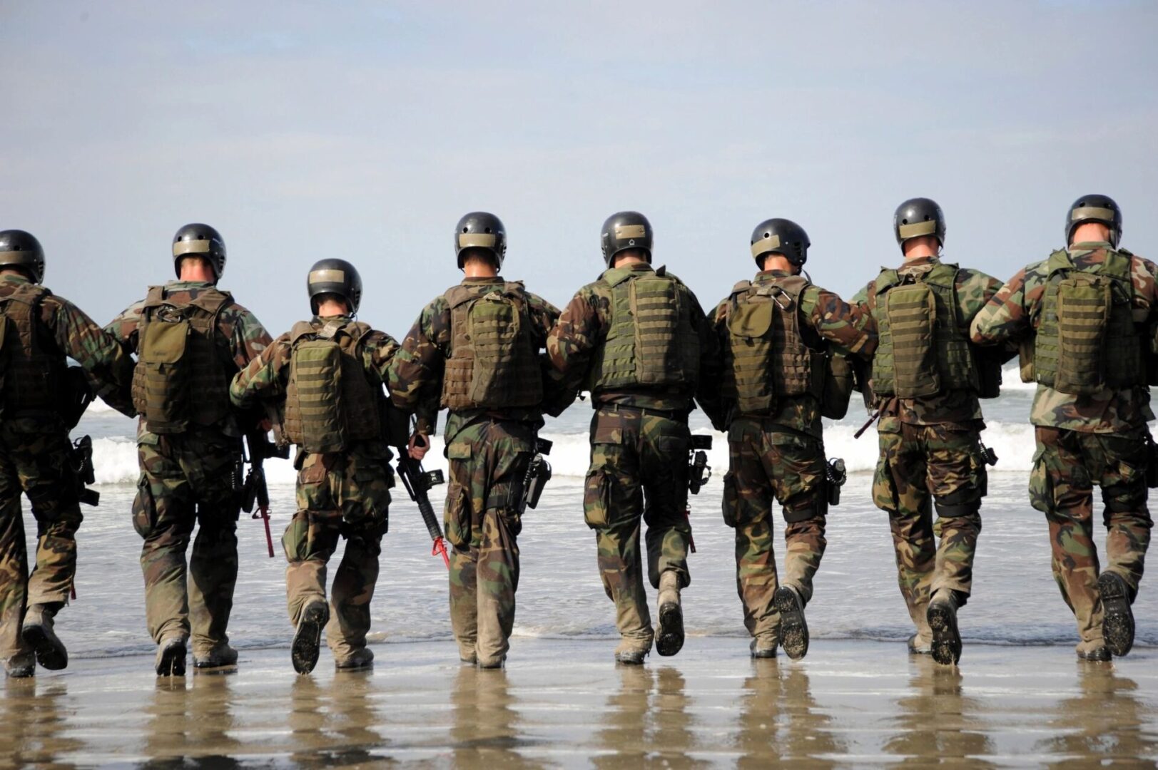 A group of soldiers walking along the beach.